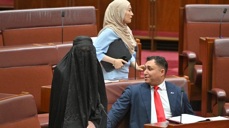 Senator Fatima Payman behind Pauline Hanson (in a burqa) in the Senate last year.