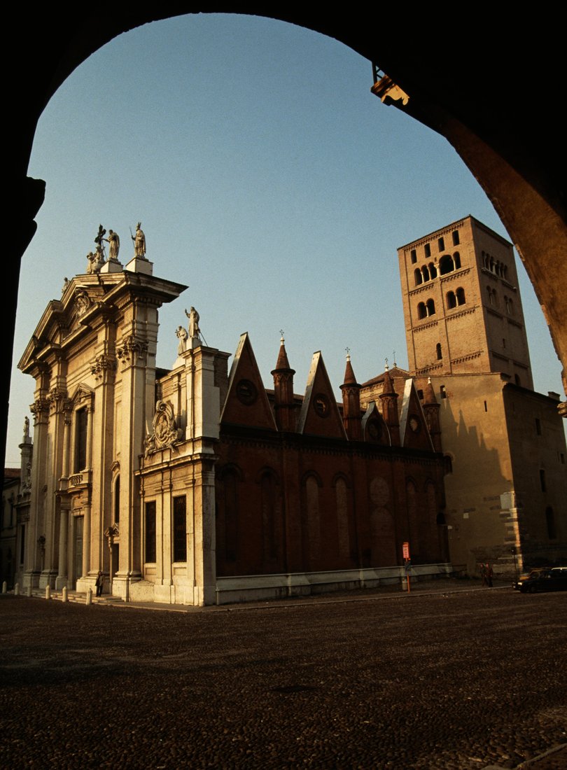 The facade, right side and Romanesque bell tower of the Cathedral of Saint Peter Apostle, Sordello square, Mantua.