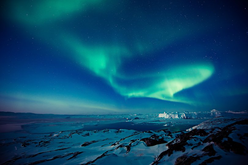 The northern lights (Aurora Borealis) over icebergs near Ilulissat.