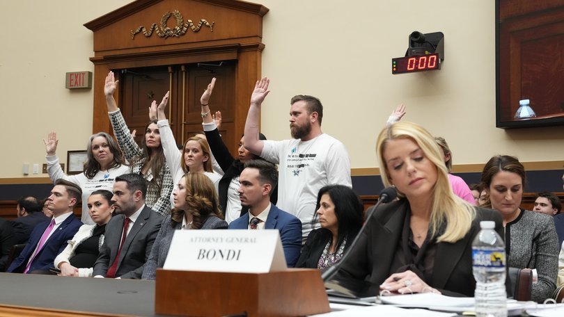 Survivors of Jeffrey Epstein wearing white t-shirts calling for a full release of the Epstein files raise their hands in response to a committee member’s question as Attorney General Pam Bondi, foreground right, testified.
