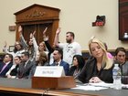 Survivors of Jeffrey Epstein wearing white t-shirts calling for a full release of the Epstein files raise their hands in response to a committee member’s question as Attorney General Pam Bondi, foreground right, testified.