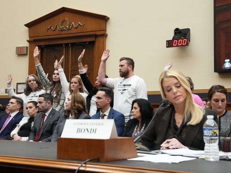 Survivors of Jeffrey Epstein wearing white t-shirts calling for a full release of the Epstein files raise their hands in response to a committee member’s question as Attorney General Pam Bondi, foreground right, testified.