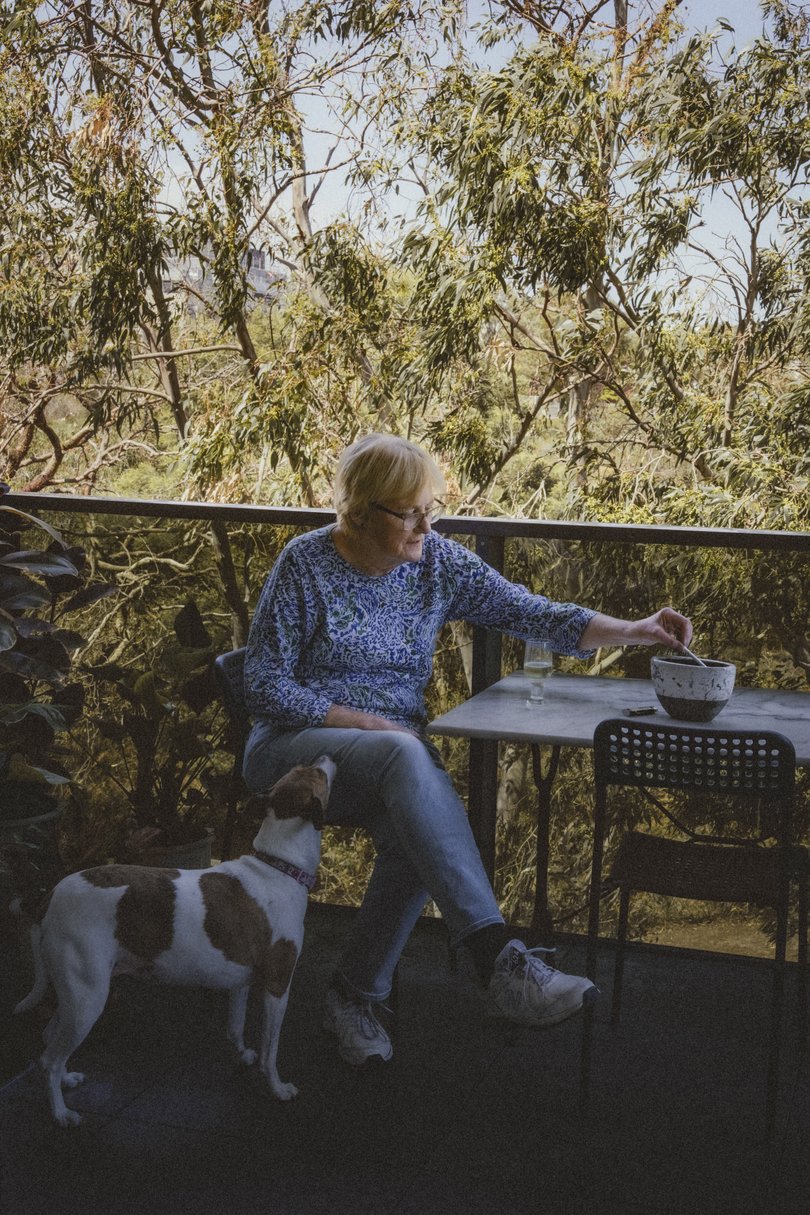 Pat Felvus drinks a glass of wine while smoking a cigarette on her balcony with her dog Minnie in Melbourne.