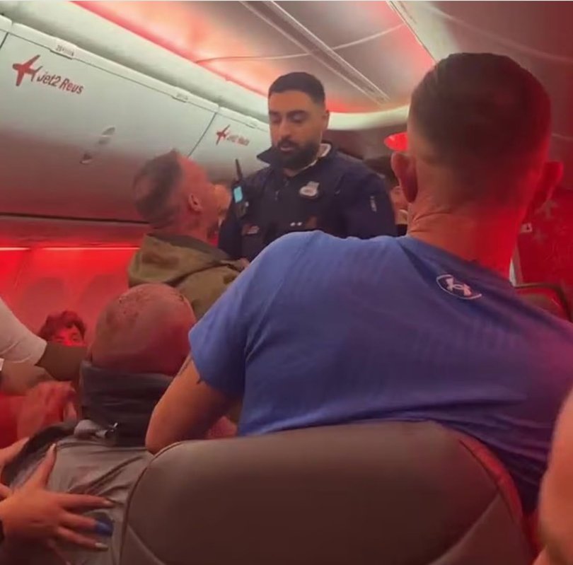 Passengers watch as aisle fight unfolds.