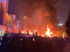 Iranian protesters gather around burning cars near a masque while blocking a street during a protest in Tehran.