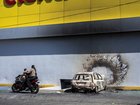 A burned car sits beside a damaged business, one day after the Mexican military killed Nemesio Oseguera Cervantes.
