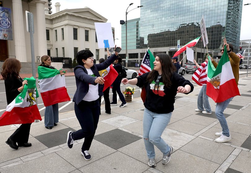 Iranians Mehrnoosh Rahbardar, left, and Hamta Farrokhi celebrate the military action against Iran in Kiener Plaza in St. Louis.