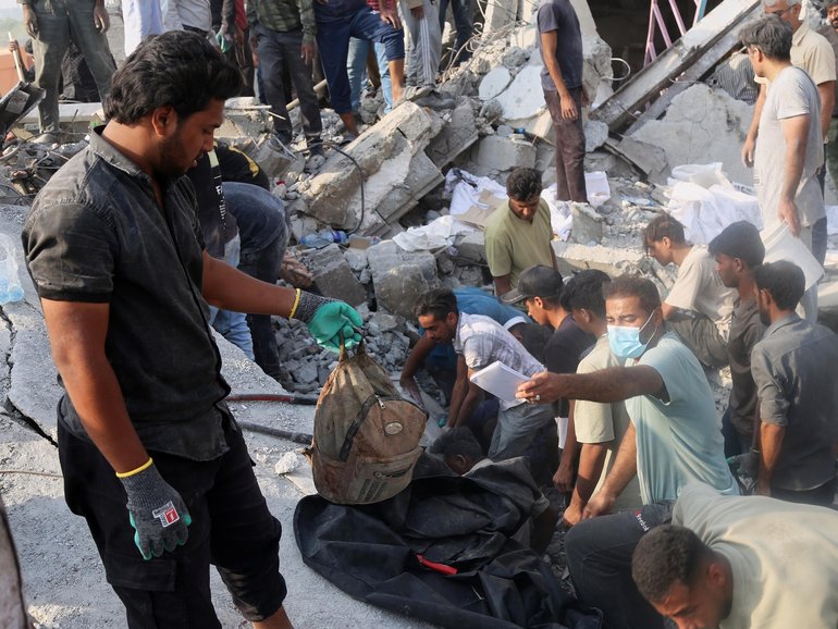 A man holds a children's backpack as rescue workers and residents search through the rubble in the aftermath of an Israeli-U.S. strike on a girls' elementary school in Minab, Iran.