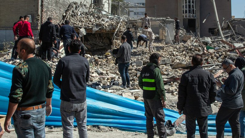 Workers in Tehran clear rubble at the site of a police station destroyed by US-Israeli airstrikes.