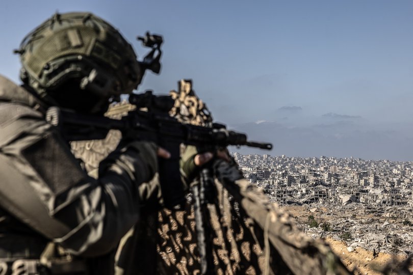 An Israeli soldier at an Israel Defense Forces outpost aims his weapon toward a ruinous Gaza City last October. 