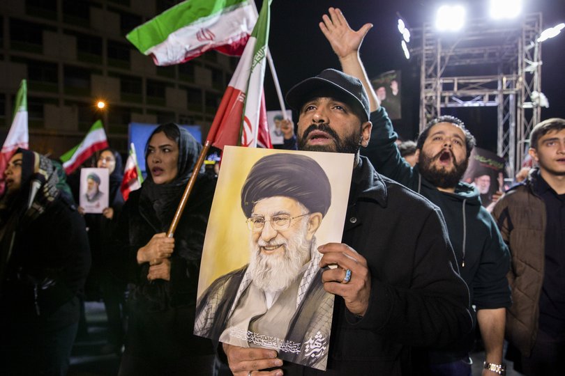 A man holds a picture of Ayatollah Ali Khamenei.