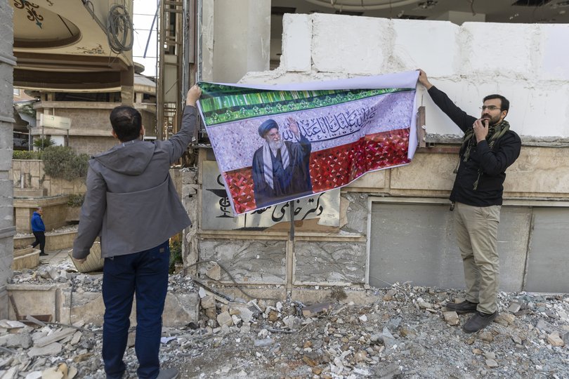 Men hang a banner depicting the late Ayatollah Ali Khamenei at a protest by medical professionals outside Gandhi Hospital, which was damaged in an airstrike earlier in this week, on March 7, 2026 in Tehran, Iran. 