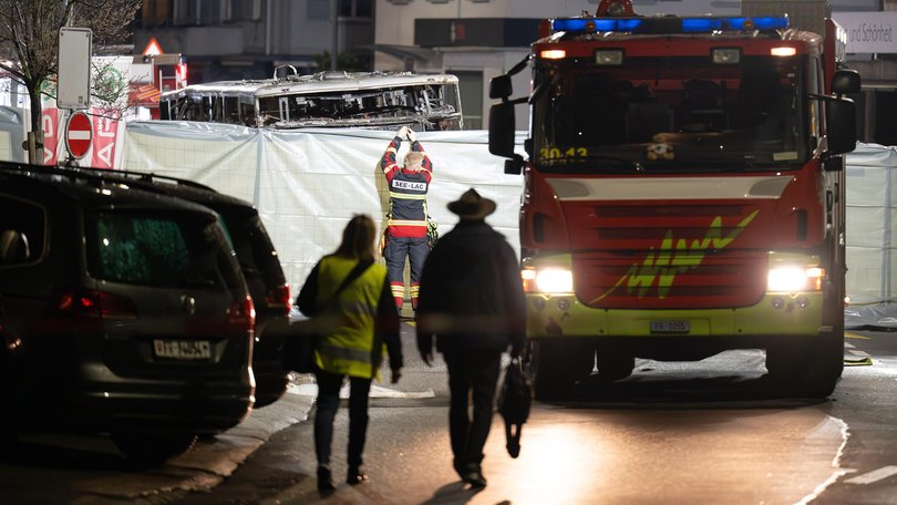 Firefighters work next to the remains of the bus.