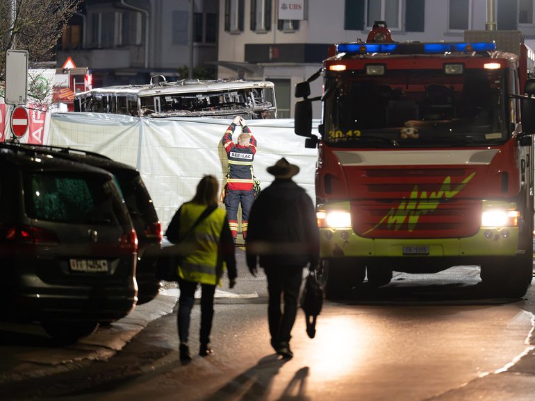 Firefighters work next to the remains of the bus.