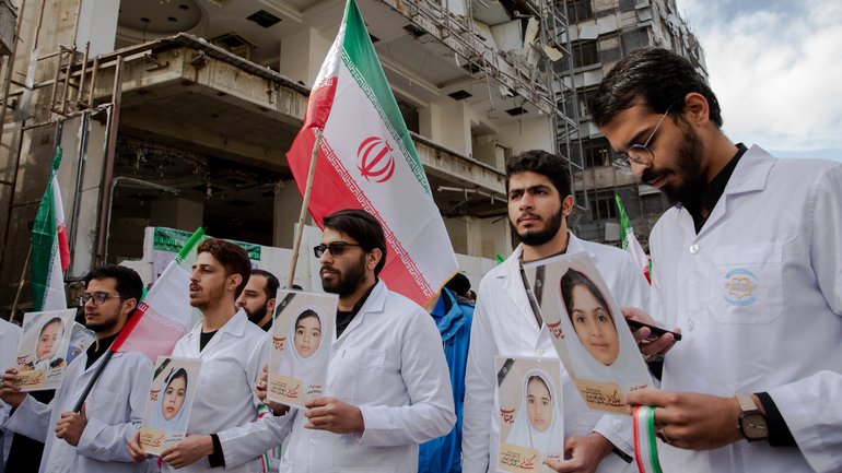 Iranian healthcare workers hold photos of schoolchildren killed in Minab during a demonstration outside the Gandhi Hospital in Tehran.