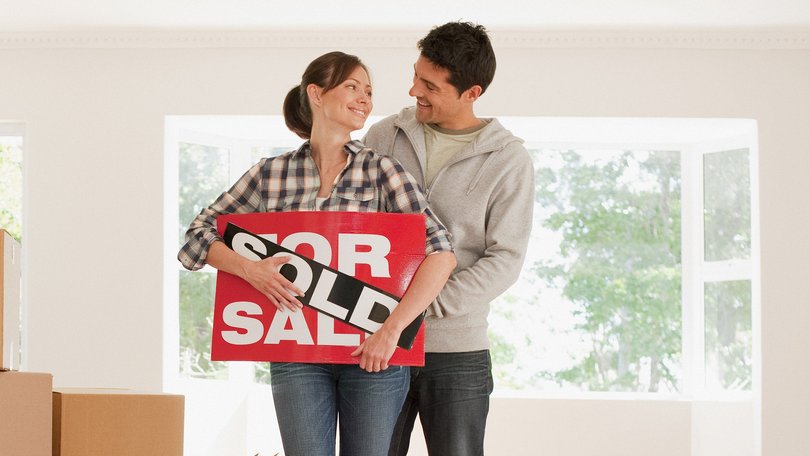 Couple holding sold sign for their new house