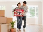 Couple holding sold sign for their new house