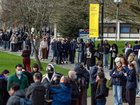 Staff and students, some wearing face masks, queue at the University of Kent in Canterbury after an outbreak of meningitis caused the deaths of two people.