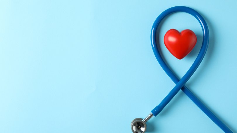 Stethoscope and heart on blue background, top view 