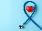 Stethoscope and heart on blue background, top view 