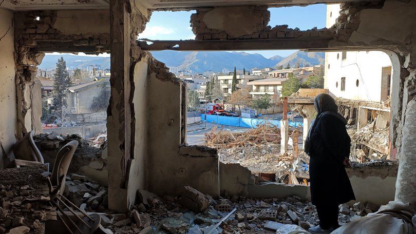A woman looks out from her destroyed apartment in Tehran, Iran.