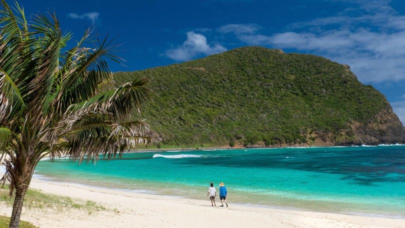 Couple enjoying a scenic walk along Neds Beach on Lord Howe Island.