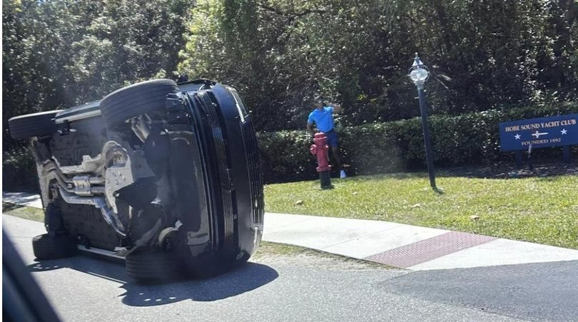 Tiger Woods standing near his rolled over car.
