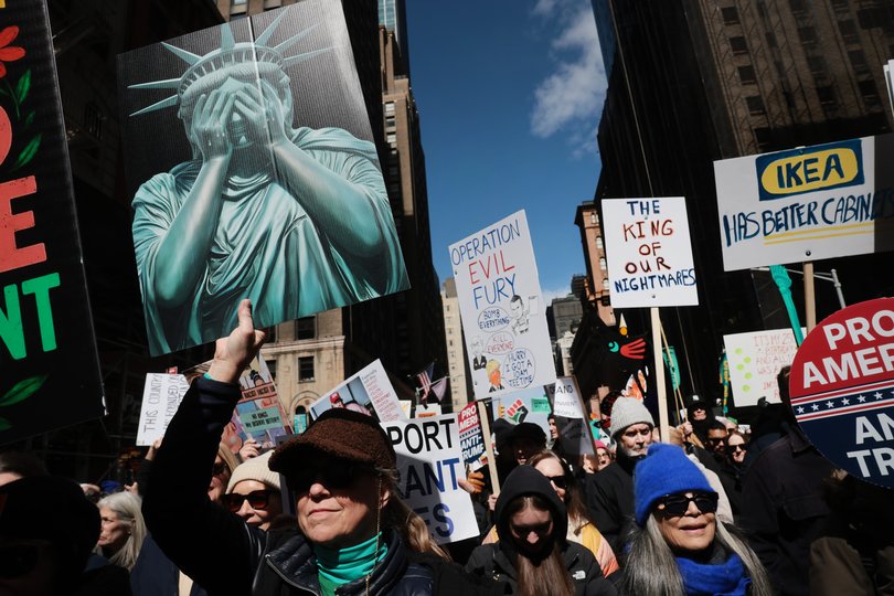 Protesters hold signs as they participate in a 'No Kings' protest in New York City. (Photo by Spencer Platt/Getty Images)