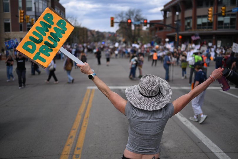 BOULDER, COLORADO - MARCH 28: Rachel Lederman waves a placard that states "DUMP TRUMP" as protestors take to the streets after marching during the No Kings march and visibility event on March 28, 2026 in Boulder, Colorado. This is the third nationwide "No Kings" protest held against the Trump administration. (Photo by Mark Makela/Getty Images)