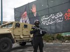 A police officer stands near an armoured-vehicle and a poster featuring the late Supreme Leader Ali Khamenei on March 28, 2026 in Tehran, Iran. 