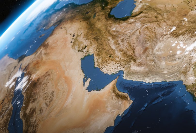 A high-angle satellite view showing the Strait of Hormuz, the Persian Gulf, and the rugged desert topography of the Middle East.