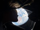 A photo provided by NASA shows NASA astronaut and Artemis II mission specialist Christina Koch as she peers out of one of the Orion spacecraft's main cabin windows, looking back at Earth, as the crew travels towards the Moon, April 4, 2026. The astronauts said they had lost track of which day it is on Earth on their transit to the moon. (NASA via The New York Times) — NO SALES; EDITORIAL USE ONLY—