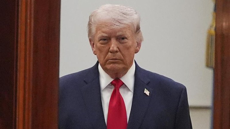 President Donald Trump pretends to aim a sniper gun while speaking with reporters.