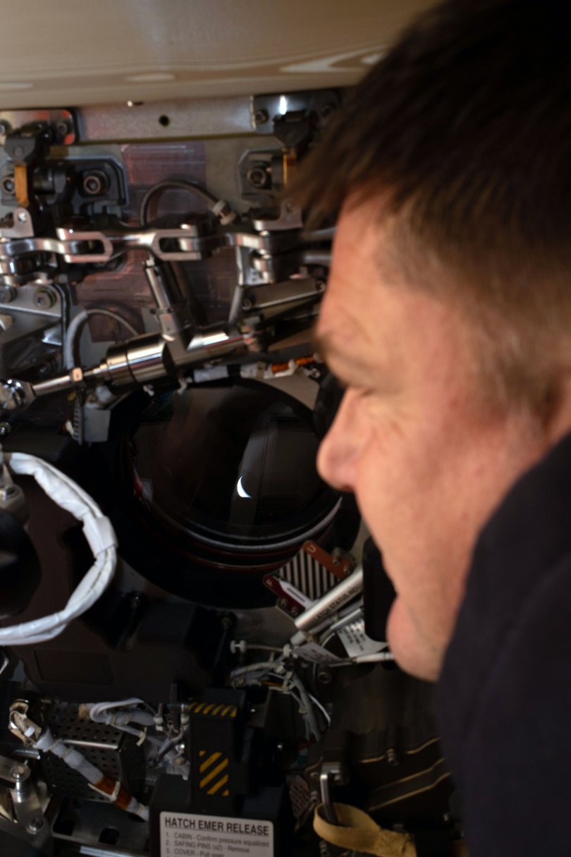 Canadian Space Agency astronaut Jeremy Hansen, a member of the Artemis II crew, looking back at the Earth from a window through a window of the Orion Integrity spacecraft.