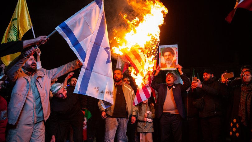 A US and Israeli flag are burned during a protest in Tehran after the ceasefire was announced.