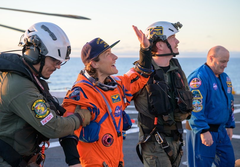 NASA astronaut Christina Koch, Artemis II mission specialist is assisted off the flight deck after arriving aboard USS John P. Murtha.