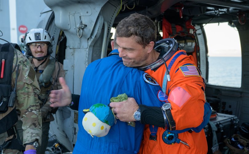 NASA astronaut Reid Wiseman, Artemis II commander, gives NASA Flight Surgeon Richard Scheuring a hug on the flight deck of USS John P. Murtha.