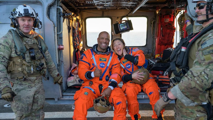 NASA astronaut Victor Glover, Artemis II pilot, left, and NASA astronaut Christina Koch, Artemis II mission specialist are seen sitting on a Navy MH-60 Seahawk.