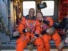 NASA astronaut Victor Glover, Artemis II pilot, left, and NASA astronaut Christina Koch, Artemis II mission specialist are seen sitting on a Navy MH-60 Seahawk.