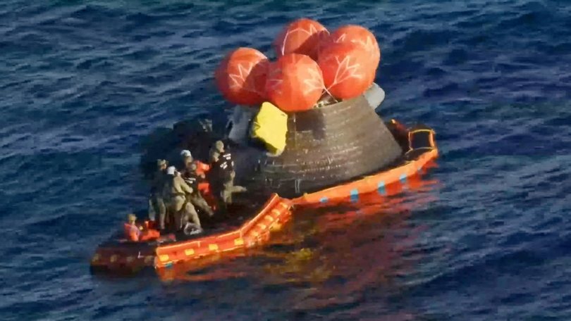 Crew members emerge from the capsule.