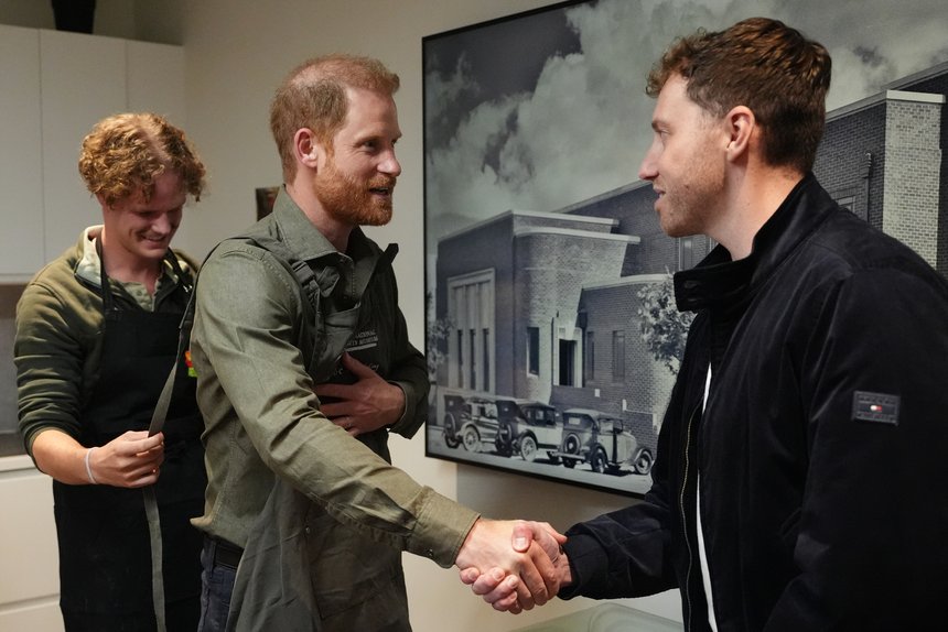 Prince Harry shakes hands with a veteran as he prepares to take part in a model making activity with veterans and their families.
