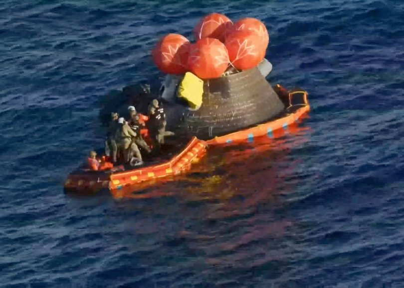 Crew members are extracted from the Artemis II crew capsule after it splashed down in the Pacific Ocean.