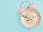 Alarm clock and plate with cutlery . Concept of intermittent fasting, lunchtime, diet and weight loss 