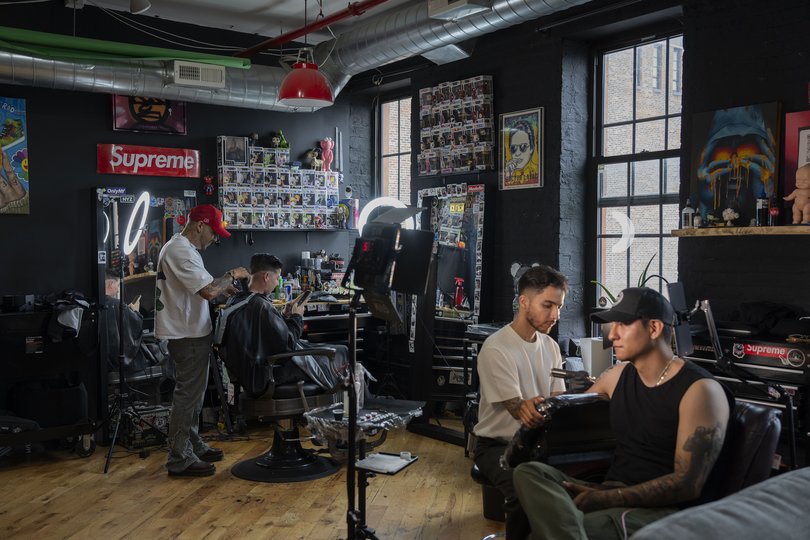 A barber and a tattoo artist work on clients at Archivio Records.