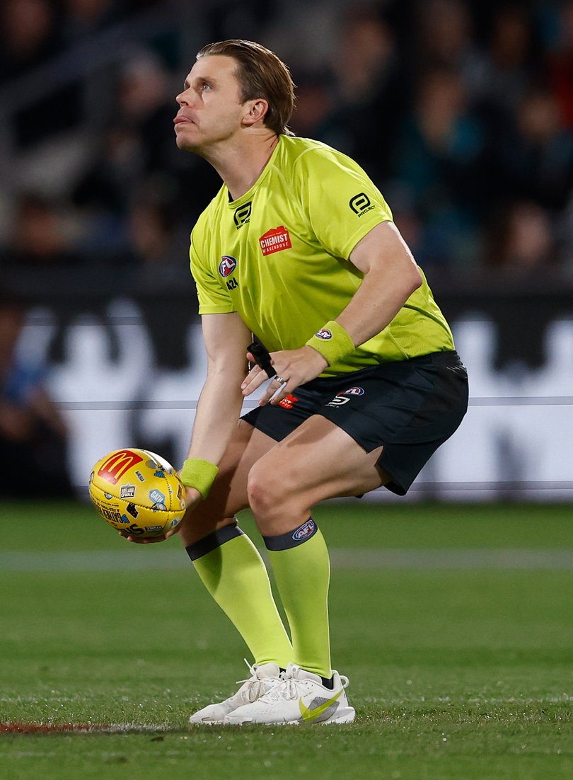 Nick Foot, AFL Field Umpire throws the ball in the air.