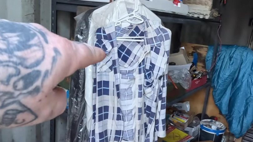 The YouTuber goes inside the shipping container, revealing it to be strewn with rubbish. Several shirts worn by Dezi are hanging up on a rack. Picture: Supplied / YouTube