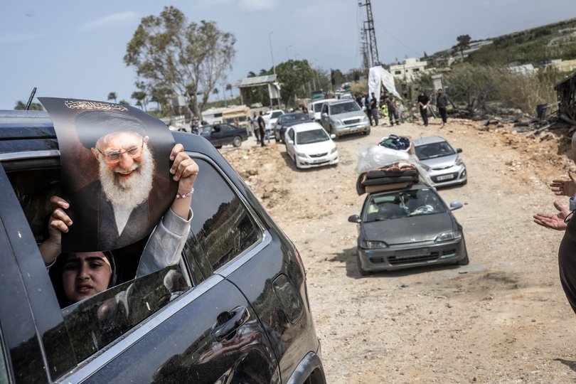A young woman holds up a portrait of the Ayatollah Ali Khamenei, the Iranian leader who was killed in U.S.-Israeli airstrikes, as returnees make their way south near Ain Abou Abdallah, Lebanon, on Friday.