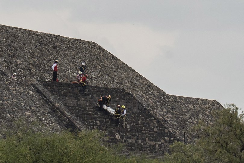 Red Cross personnel descend from the Pyramid of the Moon carrying the lifeless body of a person.