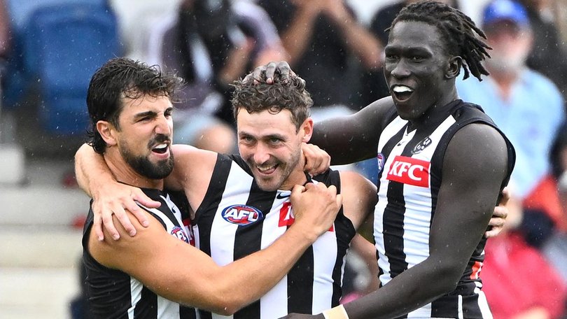 Harry Perryman is embraced by Collingwood teammates.