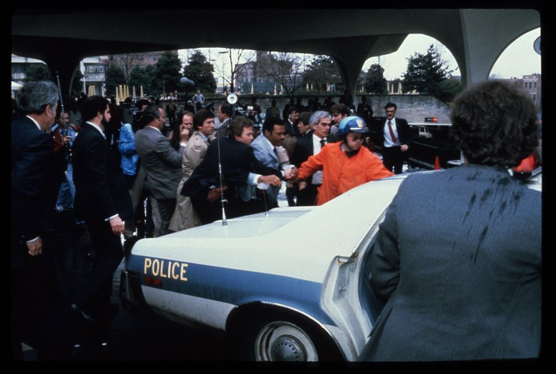 Authorities place John Hinkley into a police car shortly after his attempt to assassinate President Reagan on March 30, 1981 outside the Hilton Hotel in Washington, DC. 